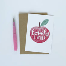 Load image into Gallery viewer, Greeting card with an apple illustration and 'lovely teacher' text, accompanied by a pink pen on a white background.