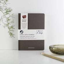 Load image into Gallery viewer, Brown notebook with white label on a light surface with a plant and candle in the background