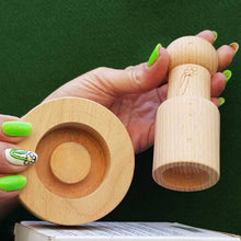 Load image into Gallery viewer, Wooden ring and cylindrical object held by a hand with green nail polish against a green background