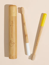 Load image into Gallery viewer, Bamboo toothbrush with yellow handle and white bristles, next to a bamboo case on a beige background.