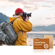 Load image into Gallery viewer, Person in yellow jacket and red beanie taking a photo with a camera, standing next to a Friendly Soap travel soap bar.