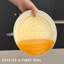 Load image into Gallery viewer, Hand holding a silicone lid with a gradient design, placed on a surface with text 'CREATES A TIGHT SEAL'.