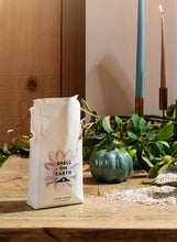 Load image into Gallery viewer, Bag of 'Shell on Earth' mulch on a wooden table with decorative elements