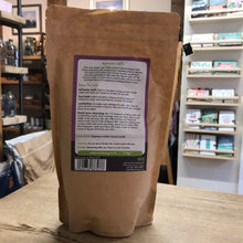 Load image into Gallery viewer, Brown paper bag with a label on a wooden surface, with shelves and products in the background.