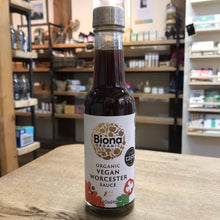 Load image into Gallery viewer, Biona Organic Vegan Worcestershire Sauce bottle on a wooden surface with shelves in the background