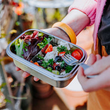 Load image into Gallery viewer, Person holding a salad in a compartmentalized container outdoors