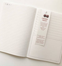 Load image into Gallery viewer, Open notebook with a cherry fruit page marker on a white surface