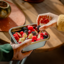 Load image into Gallery viewer, Person holding a container of mixed berries on a wooden surface
