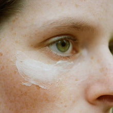 Load image into Gallery viewer, Close-up of a person's face with a white cream applied to the cheek.
