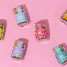 Load image into Gallery viewer, Small glass jars with cork lids on a pink background
