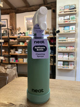 Load image into Gallery viewer, A mint green Neat refillable bottle cleaning spray standing on a wooden table inside a shop. The bottle has a white spray nozzle and a purple label that reads 'neat Refillable Bottle Cleaning Sprays'.
