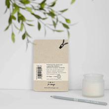 Load image into Gallery viewer, Notebook with a visible brand label on a white surface with a candle and plant in the background
