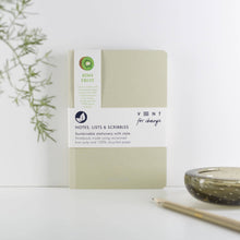 Load image into Gallery viewer, Sustainable notebook with kiwi fruit label on a white surface with a plant and pencil.

